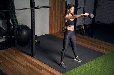 Sportif kadın spor salonunda kettlebell ile egzersiz yapıyor.