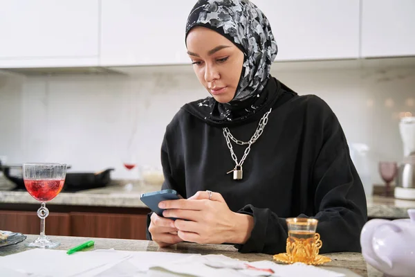 Musulmane travaillant en ligne sur smartphone à la maison — Photo