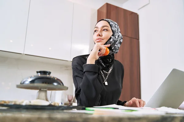 Mulher muçulmana feliz com laptop e tangerina — Fotografia de Stock