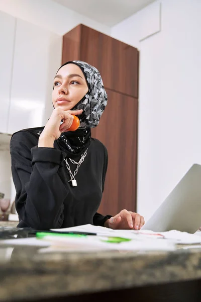 Femeia musulmană relaxată cu mandarină și notebook în interior — Fotografie, imagine de stoc