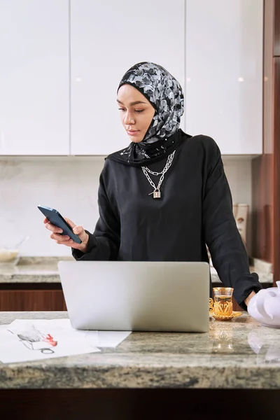 Muslimská mladá žena s gadgets v kuchyni — Stock fotografie