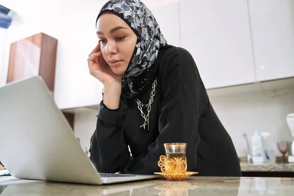 Jovem mulher muçulmana com laptop e chá em casa — Fotografia de Stock