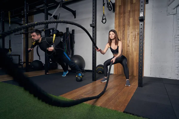 Atletik erkek ve kadın spor salonunda birlikte çalışıyor.