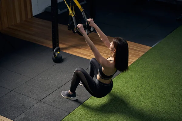 Спортивна жінка використовує висячі тренувальні ремені в тренажерному залі — стокове фото