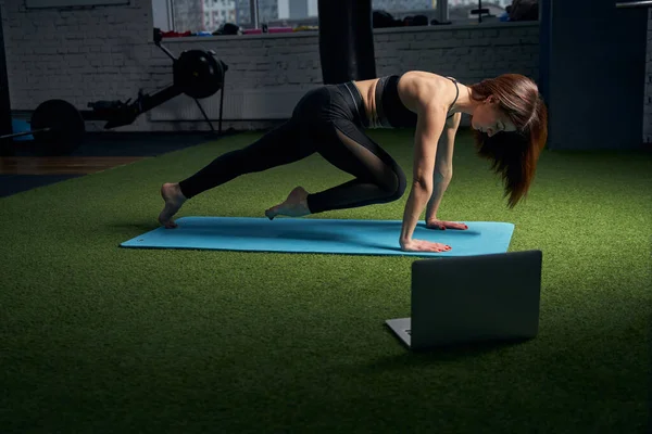 Mulher fazendo exercício e usando notebook no estúdio de fitness — Fotografia de Stock
