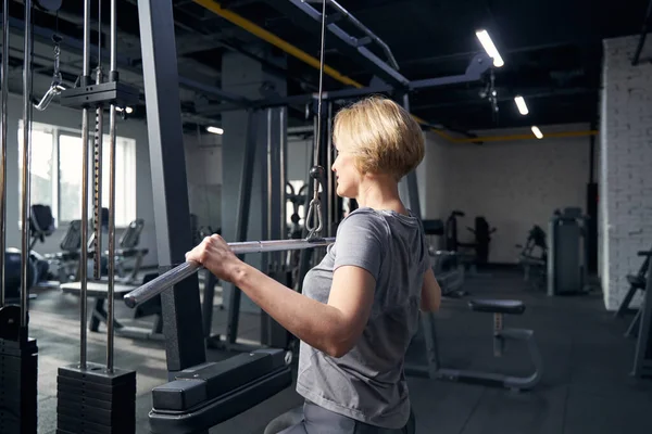 Kobieta korzystająca ze sprzętu gimnastycznego podczas treningu siłowego — Zdjęcie stockowe