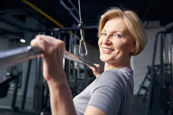 Mujer alegre haciendo ejercicio de fuerza en el gimnasio — Foto de Stock