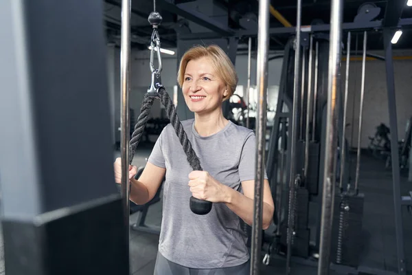 Mujer alegre usando equipo de gimnasio durante el entrenamiento —  Fotos de Stock
