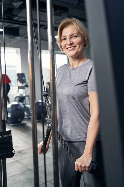 Mujer alegre usando equipo de gimnasio durante el entrenamiento — Foto de Stock