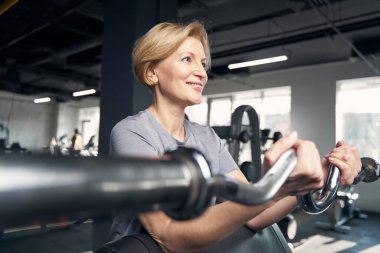 Gülümseyen kadın spor hocasıyla egzersiz yapıyor.