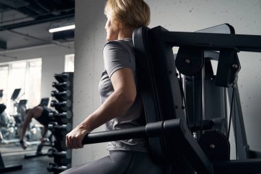 Spor salonunda spor aletleri kullanan bir kadın.
