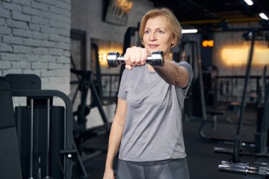 Spor salonunda halterle egzersiz yapan bir kadın.