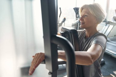 Spor salonunda spor yapan neşeli bir kadın.