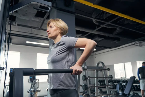 Spor kıyafetli bir kadın spor salonunda egzersiz yapıyor.