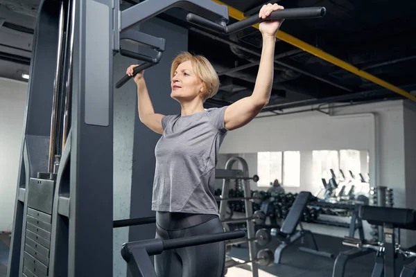 Spor salonunda spor aletleri kullanan bir kadın.