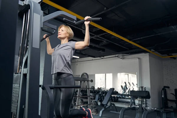 Mujer en ropa deportiva haciendo ejercicio con equipo de gimnasio — Foto de Stock