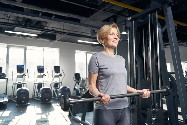 Mujer alegre haciendo ejercicio con barra en el gimnasio —  Fotos de Stock