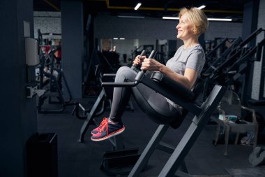 Spor salonunda spor aletleri kullanan neşeli bir kadın.