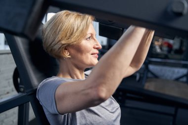 Spor salonunda spor aletleri kullanan neşeli bir kadın.