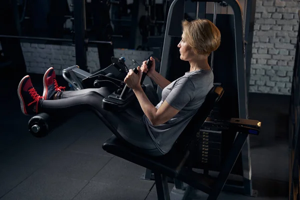 Mujer en ropa deportiva usando la máquina de fitness en el gimnasio — Foto de Stock