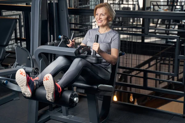 Mujer sonriente usando equipo de fitness en el gimnasio — Foto de Stock