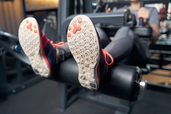 Kvinnliga ben i sneakers vilar på träningsmaskin i gymmet — Stockfoto