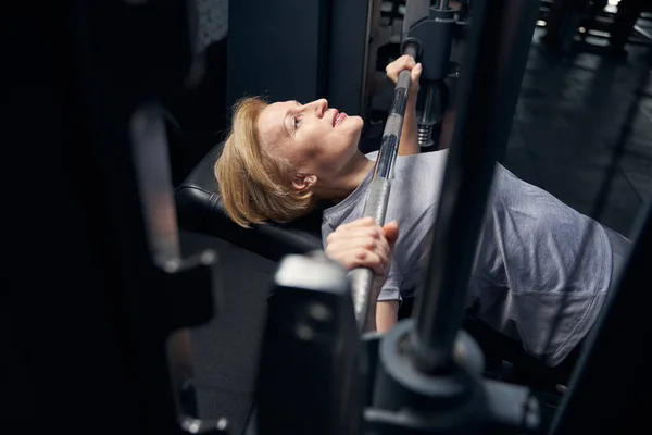 Mujer usando barra de prensa máquina de banca en el gimnasio — Foto de Stock