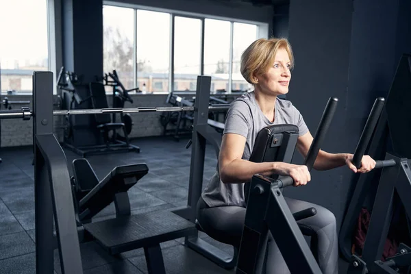 Mujer sonriente usando equipo de fitness en el gimnasio — Foto de Stock