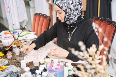 Müslüman kadın tasarımcı el yapımı kıyafetler yapmak için boya kullanıyor.