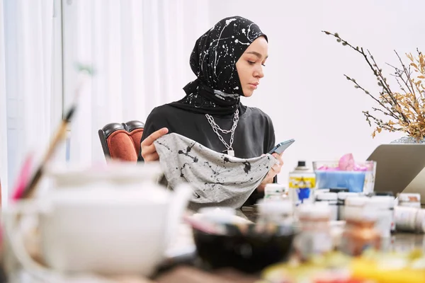 Jeune femme musulmane coudre des vêtements traditionnels dans un studio moderne — Photo