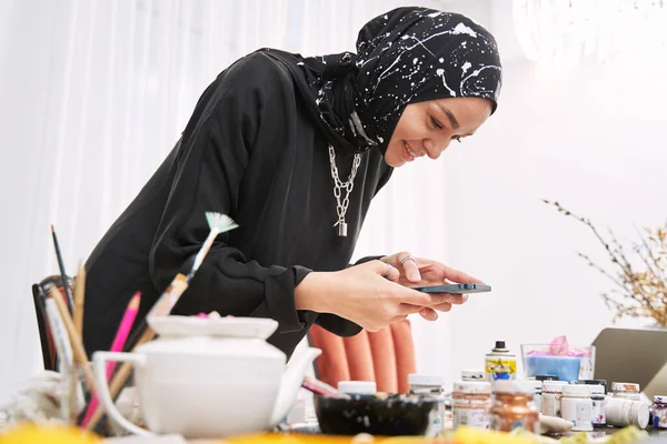 Souriant créateur de mode musulman en utilisant smartphone en studio — Photo