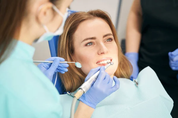 Dentysta wykonujący leczenie zębów urządzeniem stomatologicznym — Zdjęcie stockowe