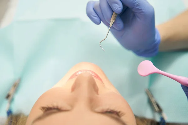 Dentista examinando dientes de mujer con herramientas dentales — Foto de Stock