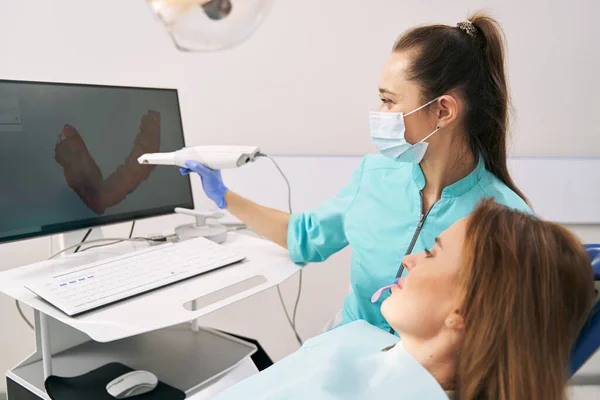 Dentista mostrando resultados de escaneo 3D dental a mujer en clínica —  Fotos de Stock