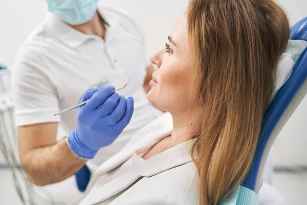 Odontólogo masculino examinando dientes de mujer con herramienta dental —  Fotos de Stock