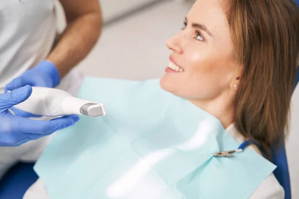 Doctor with dental device sitting next to woman in clinic — Stock Photo, Image