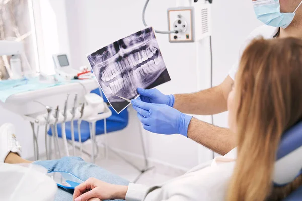 Médico mostrando una radiografía dental a una mujer en la clínica —  Fotos de Stock