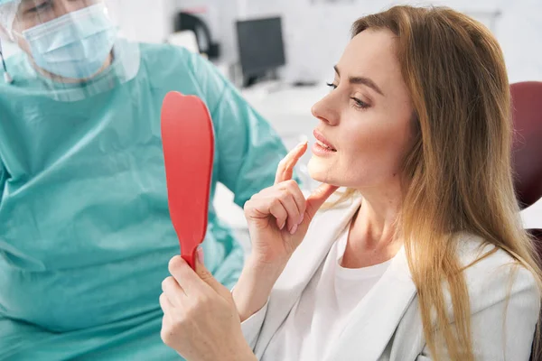 Női beteg néz a tükörbe a fogászati klinikán. — Stock Fotó