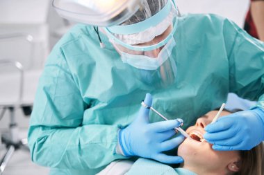 Erkek dişçi stomatoloji kliniğinde dişçilik yapıyor.