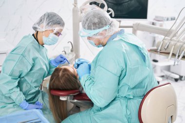 Dişçiler stomatoloji kliniğinde diş tedavisi uyguluyorlar