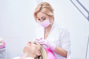 Konsantre kadın dermatolog saç mezoterapisi prosedürü uyguluyor.