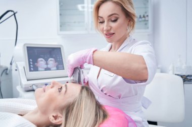 Kozmetikçi müşteri üzerinde cilt sıkma prosedürü uyguluyor