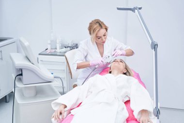 Ciddi konsantre güzellik uzmanı kaş kaldırma prosedürü uyguluyor.