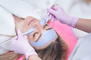 Kadın yüz derisine maske takan dermatolog.