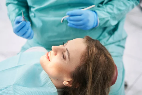 Vrouw liggend in tandartsstoel in tandartspraktijk — Stockfoto