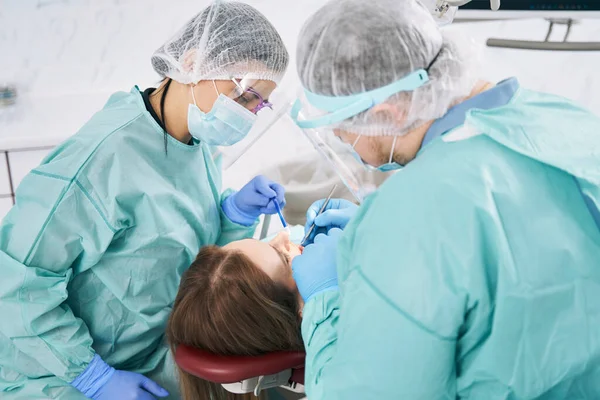 Lekarze prowadzący leczenie stomatologiczne dla kobiet w klinice — Zdjęcie stockowe