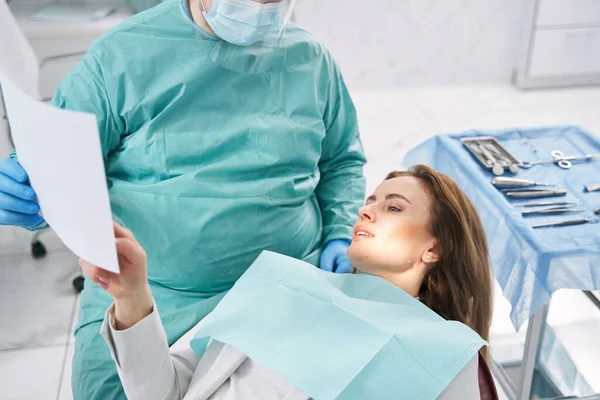 Médico mostrando exploración dental a mujer en clínica de estomatología —  Fotos de Stock