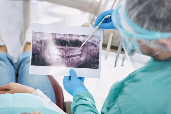 Dentista mostrando radiografía dental a mujer en clínica de estomatología — Foto de Stock