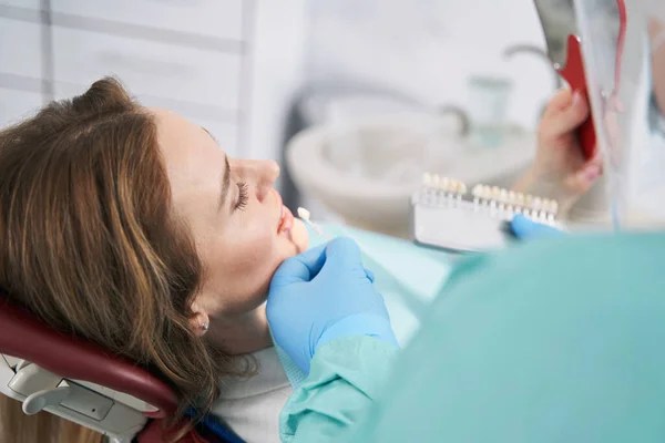 Dentista elegir el color de los dientes de la mujer antes del tratamiento dental — Foto de Stock