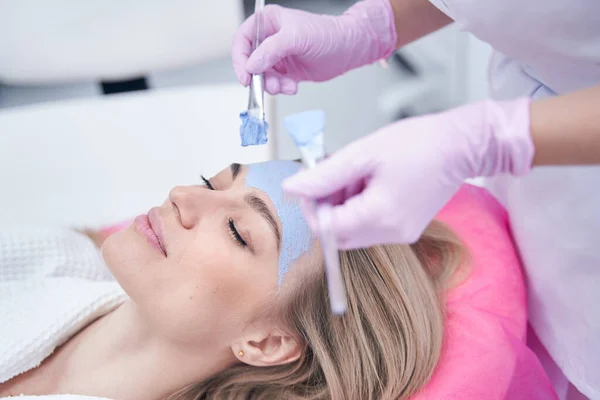 Kosmetologe mit zwei Pinseln beim Auftragen der Gesichtsmaske — Stockfoto